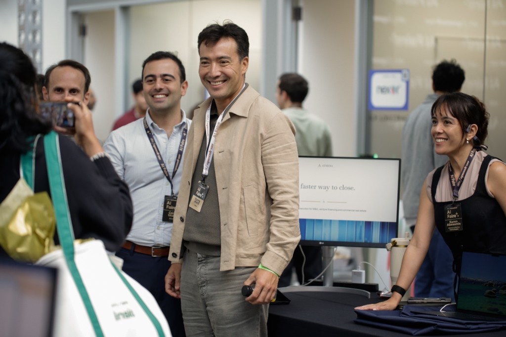 Smiling guests and a founder at their demo table during AI Faire