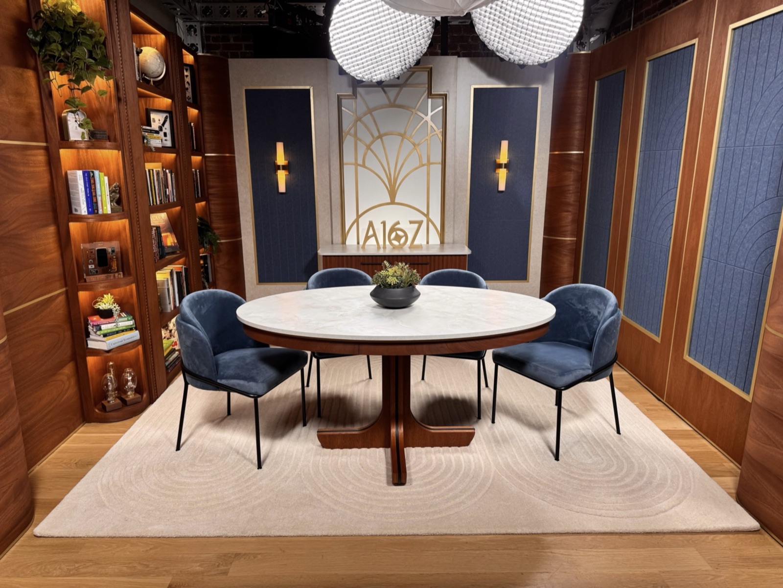 A round table and blue chairs in the a16z studio set