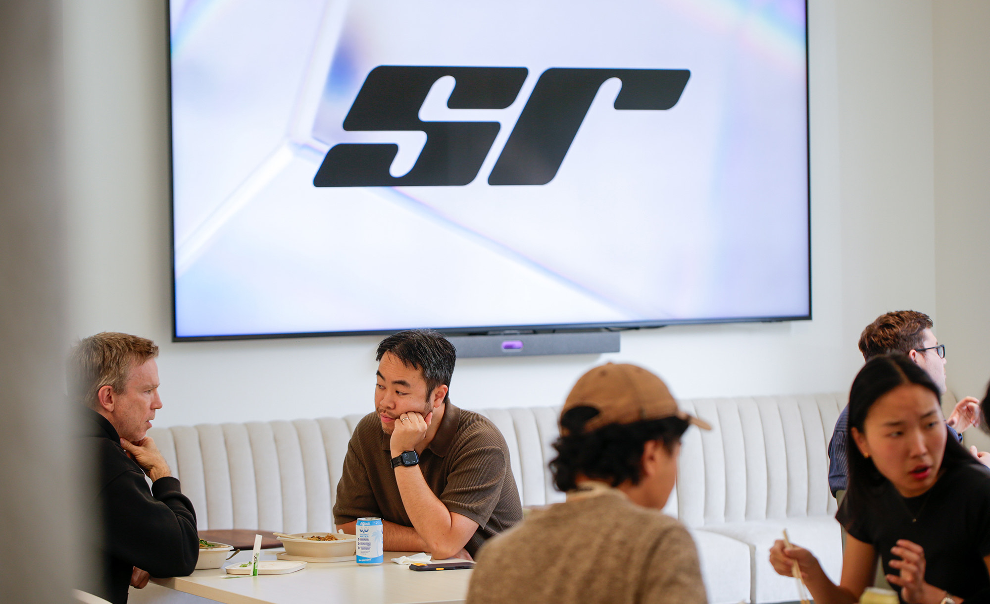 Founders and visitors having lunch in front of the SR logo on the speedrun floor