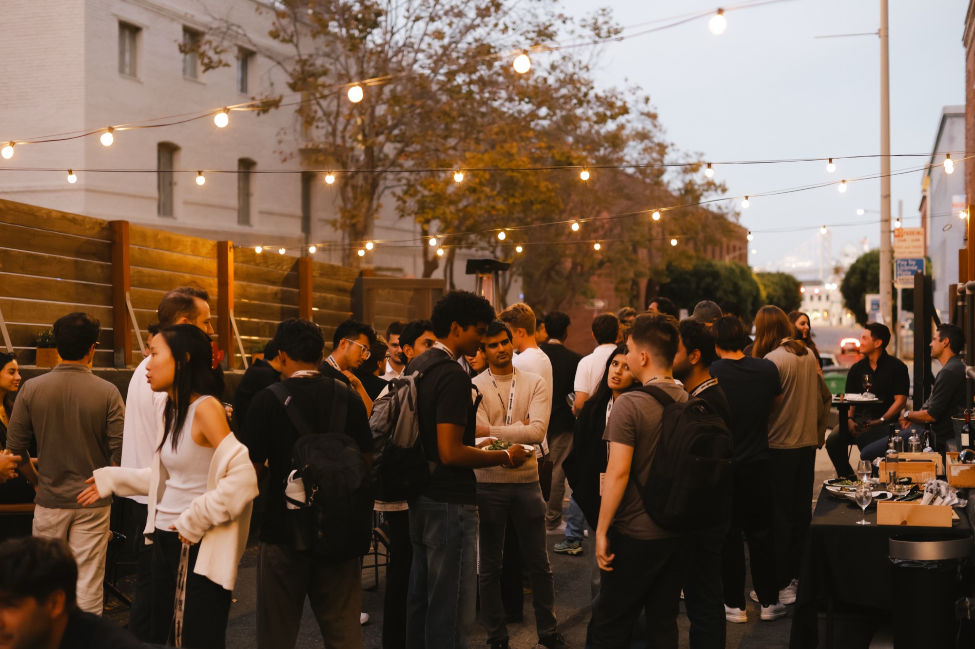Founders talking at an outdoor speedrun mixer under string lights